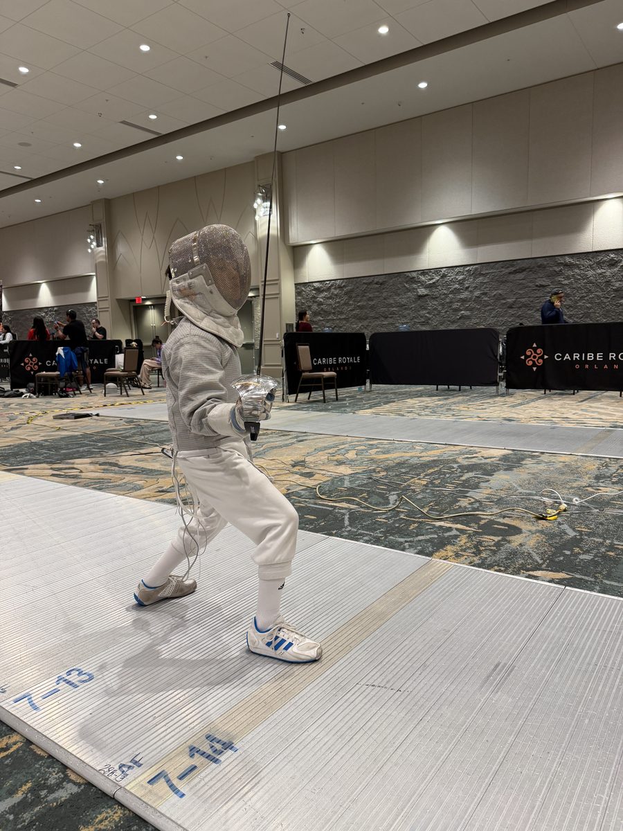 Young CSFA fencer in en garde position on competition strip